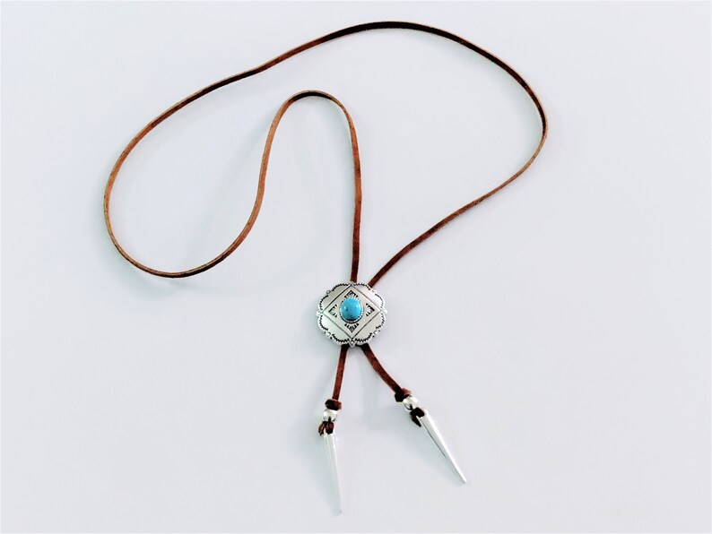 Western Bolo tie necklace for women girls, an Aztec style ancient silver metal round slider flower Concho with a oval shape turquoise gemstone decoration slide over a 34 inch length saddle tan leather lace, silver spikes décor both leather ends