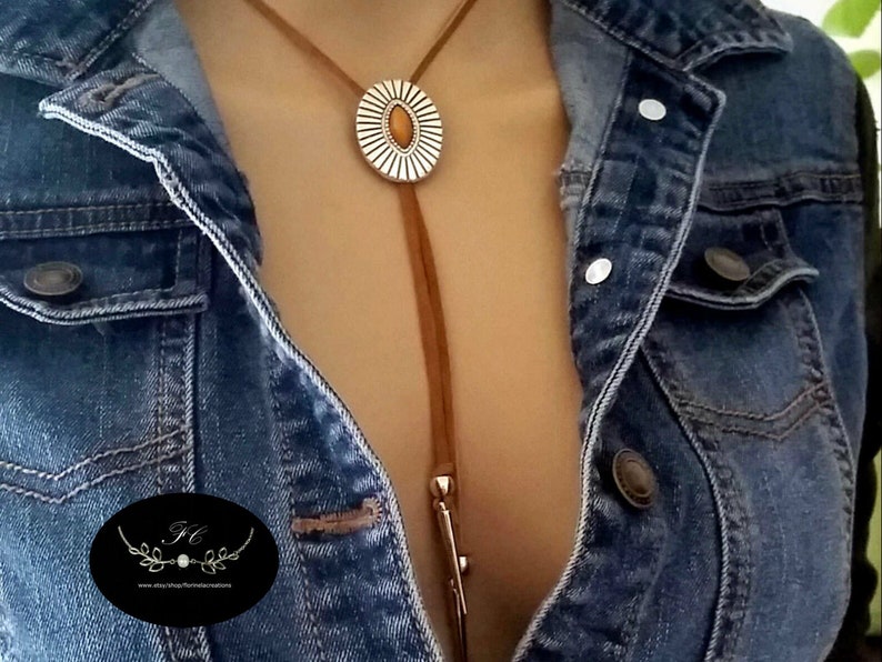 Western Bolo tie necklace for women girls, an Aztec style ancient silver metal oval slider flower Concho with a marquise shape tiger eye gemstone decoration slide over a 34 inch length saddle tan leather lace, silver spikes décor both leather ends