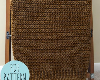 May include: A brown crocheted blanket with a textured pattern. The blanket is displayed on a wooden easel with the text "PDF PATTERN" on a blue circle.