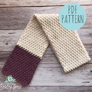 May include: A crocheted scarf with a two-tone color pattern. The scarf is made with a beige yarn with flecks of color and a burgundy yarn. The scarf is laid out on a wooden surface with the text "PDF PATTERN" in a circle.