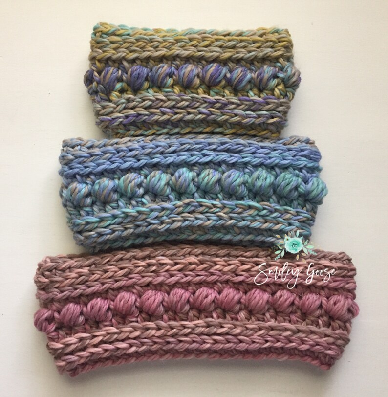 Puede incluir: Tres diademas de crochet en diferentes colores. La diadema superior es una mezcla de morado, azul y verde. La diadema del medio es una mezcla de azul, verde y gris. La diadema inferior es una mezcla de rosa y marr&oacute;n. Las tres diademas tienen un dise&ntilde;o texturizado y abultado.