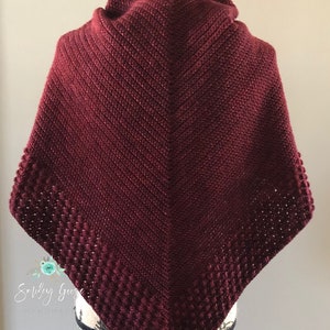 May include: A burgundy crocheted shawl with a textured border. The shawl is draped over a black mannequin.