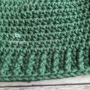 May include: Close-up of a green crocheted fabric with a textured pattern. The fabric is made with a single crochet stitch and has a smooth, even texture.
