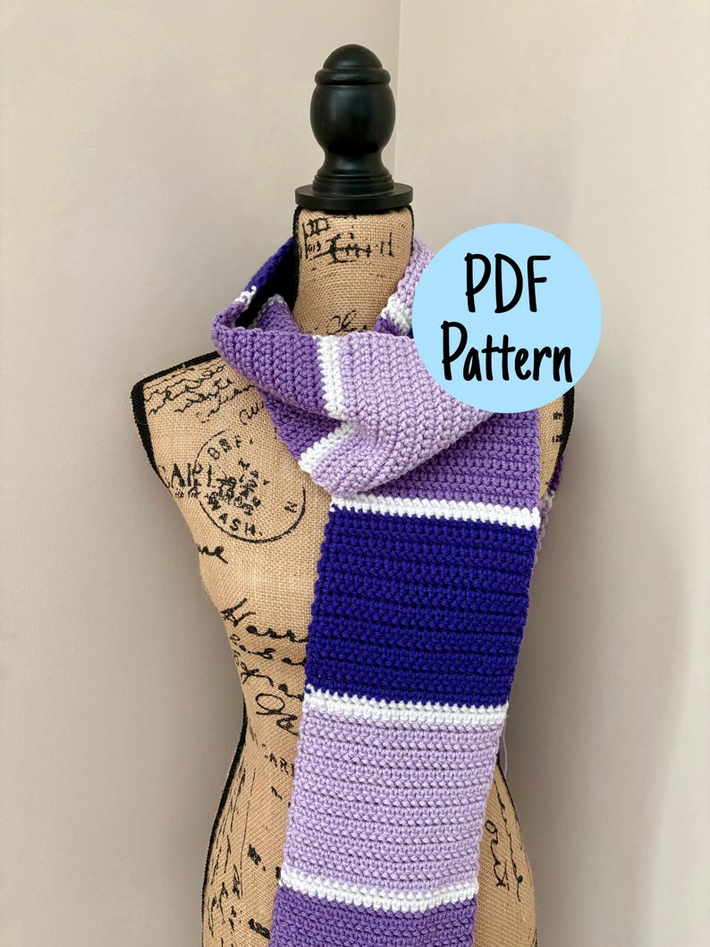 Puede incluir: Una bufanda de ganchillo con rayas horizontales en tonos morado claro, morado oscuro y blanco. La bufanda se muestra en un maniqu&iacute;. Un gr&aacute;fico circular azul claro con el texto negro PDF Pattern est&aacute; superpuesto en la imagen.