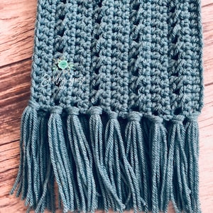 May include: A teal blue crocheted scarf with a fringe on the bottom edge.