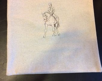 以下が含まれることがあります： 白地に黒と白の線画で描かれた、馬に乗っている人の絵がプリントされた白い枕カバー。人物はシルクハットをかぶり、馬術の姿勢で乗っています。