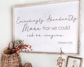 May include: A white sign with the text "Exceedingly Abundantly More than we could ask or imagine. Ephesians 3:20" hanging on a white wall above a fireplace mantel. The mantel is decorated with a wicker basket, books, a wooden bead garland, a glass vase with dried branches, and a framed print of an owl.