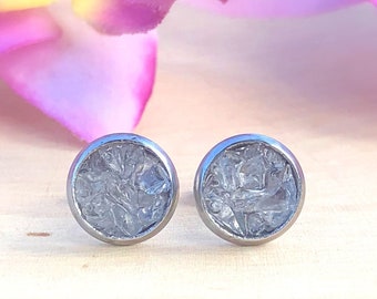 Peut inclure: Une paire de boucles d'oreilles clous argentées avec un motif rond texturé transparent.