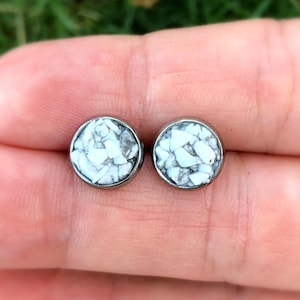 May include: A pair of silver stud earrings with white speckled round insets.