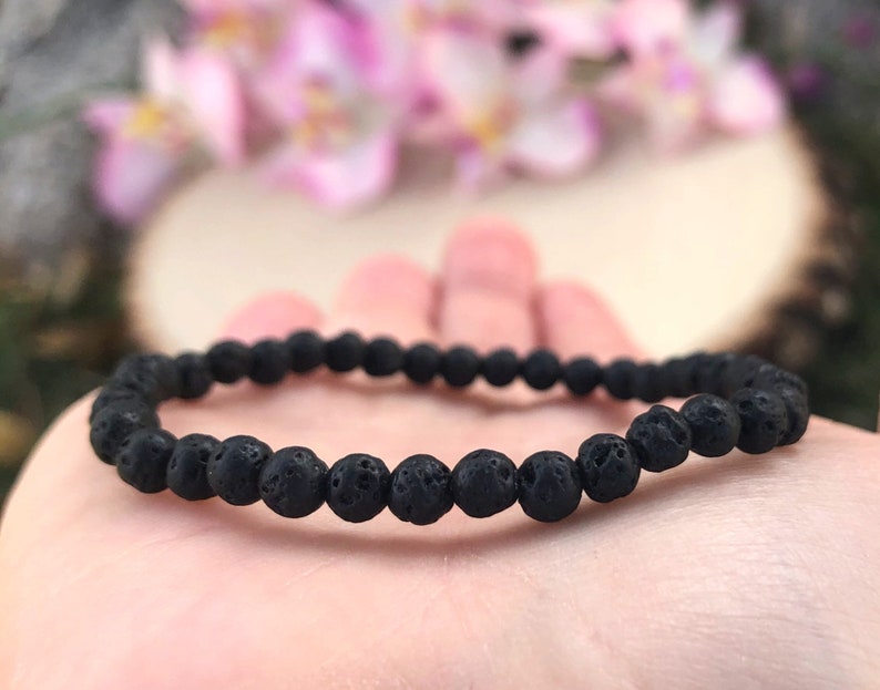 May include: A black lava rock beaded bracelet. The bracelet is made of small, round beads that are strung together on a thin elastic cord.