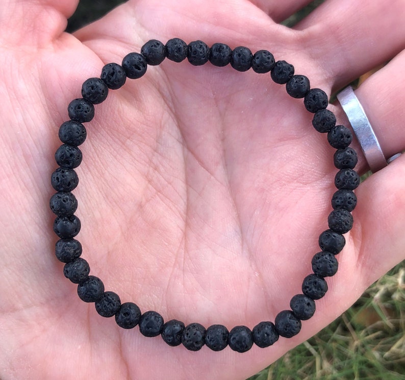 May include: A black lava rock beaded bracelet. The bracelet is made of small, round beads with a rough, textured surface.