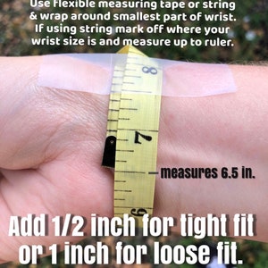 May include: A yellow measuring tape wrapped around a wrist, measuring 6.5 inches. The image includes text explaining how to measure wrist size using tape or string, and how to add inches for a tight or loose fit.