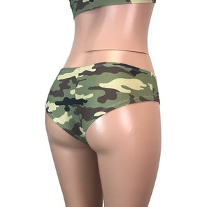 May include: Green, brown and black camouflage print underwear with a low rise and a cheeky cut.