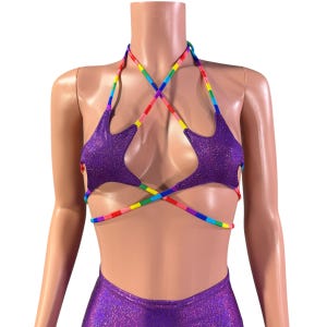 Può includere: Top halter viola a forma di stella con spalline arcobaleno. Il top è realizzato in tessuto scintillante e ha un design incrociato sul davanti.