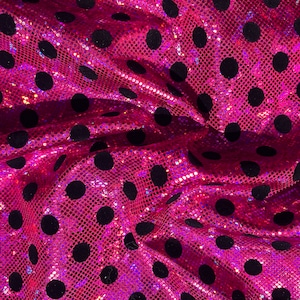 Puede incluir: Primer plano de una vibrante tela rosa con textura de lentejuelas. La tela está adornada con grandes lunares negros espaciados uniformemente. El material está recogido, creando pliegues y sombras que realzan la textura visual y la profundidad del diseño.