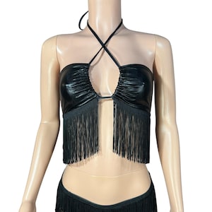 May include: A black halter top with a shiny, faux leather fabric and fringe trim. The top has a criss-cross halter strap and a keyhole opening in the front.