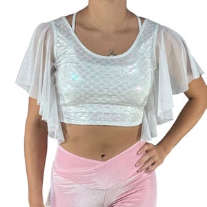 May include: White crop top with a mermaid scale pattern and sheer white angel sleeves. The top is made of a stretchy, iridescent fabric.