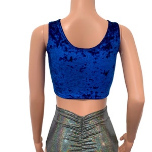May include: A royal blue velvet crop top with a scoop neckline. The top is paired with silver, iridescent, ruched shorts. The outfit is displayed on a mannequin against a white background. The fabric of the top has a textured appearance.