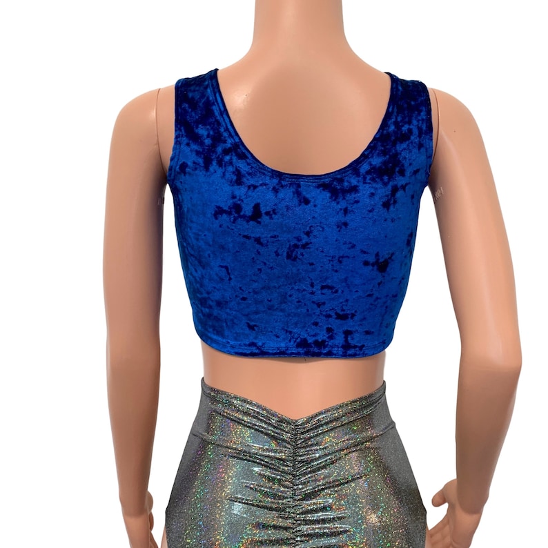 May include: A royal blue velvet crop top with a scoop neckline. The top is paired with silver, iridescent, ruched shorts. The outfit is displayed on a mannequin against a white background. The fabric of the top has a textured appearance.
