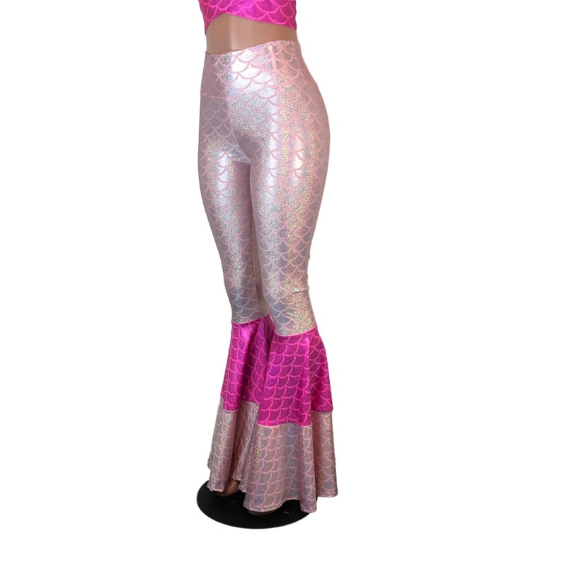 May include: Pink and silver mermaid scale print flared trousers with a pink ruffle trim.