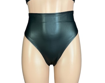 Puede incluir: Pantalones cortos negros de cintura alta hechos de cuero sintético. Los pantalones cortos tienen un corte de pierna alto y un acabado liso y brillante.