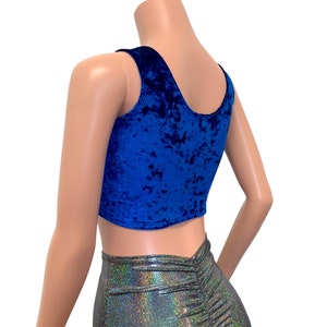 May include: A royal blue velvet crop top with a scoop neckline. The top is sleeveless and has a textured appearance. The bottom of the top is cut straight across. The model is wearing a silver, iridescent skirt.