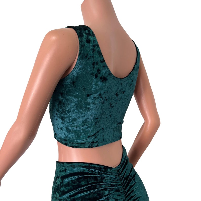 May include: A green velvet crop top and matching skirt. The top has a scoop neck and sleeveless design. The skirt has a high waist and a gathered detail in the back.