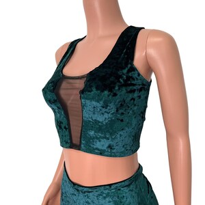 May include: A green velvet crop top with a black mesh panel in the front. The top has a scoop neckline and thin straps.