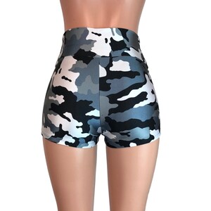 May include: Black, white, and gray camouflage print high-waisted shorts. The shorts are made of a shiny, stretchy fabric.