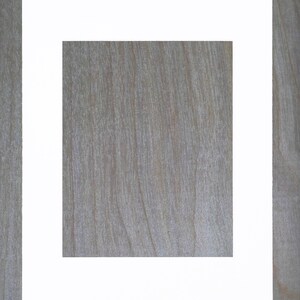 May include: A white picture frame with a thick border, set against a woodgrain background.