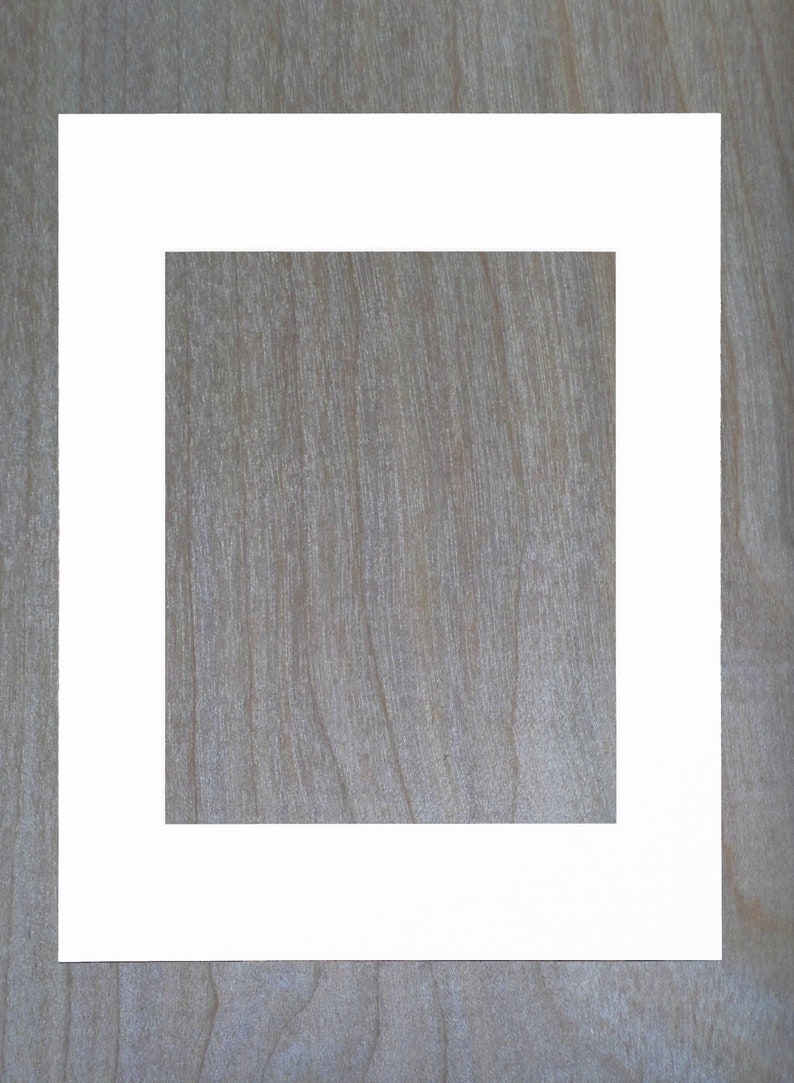 May include: A white picture frame with a thick border, set against a woodgrain background.