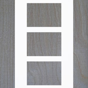 May include: A white picture frame with three rectangular openings. The frame is on a woodgrain background.