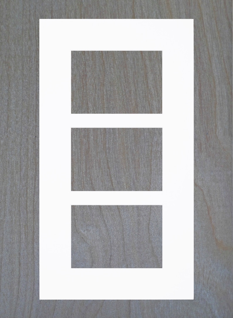 May include: A white picture frame with three rectangular openings. The frame is on a woodgrain background.