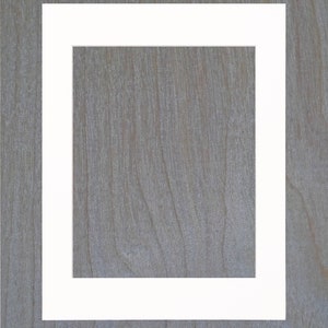 May include: A white picture frame with a thick border, against a woodgrain background.