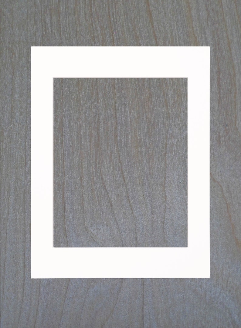 May include: A white picture frame with a thick border, against a woodgrain background.