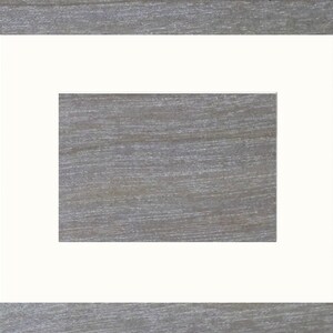 May include: A white picture frame with a white mat, creating a double border around the opening. The frame is on a woodgrain background.