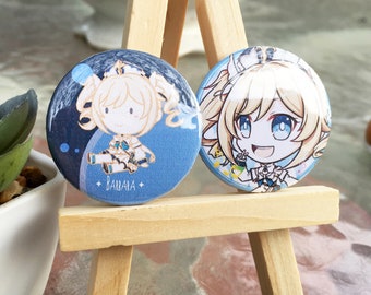 May include: Two round, blue and white character badges. One features a chibi-style illustration of a blonde character with the name "BAUARA" below. The other badge shows a similar character with a cheerful expression.