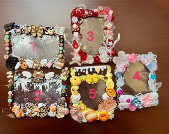 May include: Five decorative picture frames with various embellishments. Frames are adorned with miniature sweets, bows, and other decorative elements. Each frame has a different number in the center. The frames are in shades of brown, white, pink, and yellow.