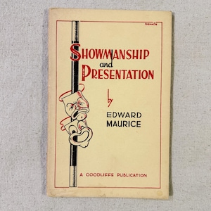 Op de afbeelding: Een vintage boek getiteld Showmanship and Presentation door Edward Maurice, een Goodliffe-publicatie. De crèmekleurige kaft bevat rode tekst, een illustratie van een zwarte toverstaf en twee theatermaskers in zwart-wit.