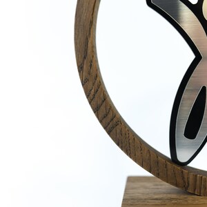 May include: A wooden award with a silver and black figure on top. The figure is a stylised person with arms raised in the air.