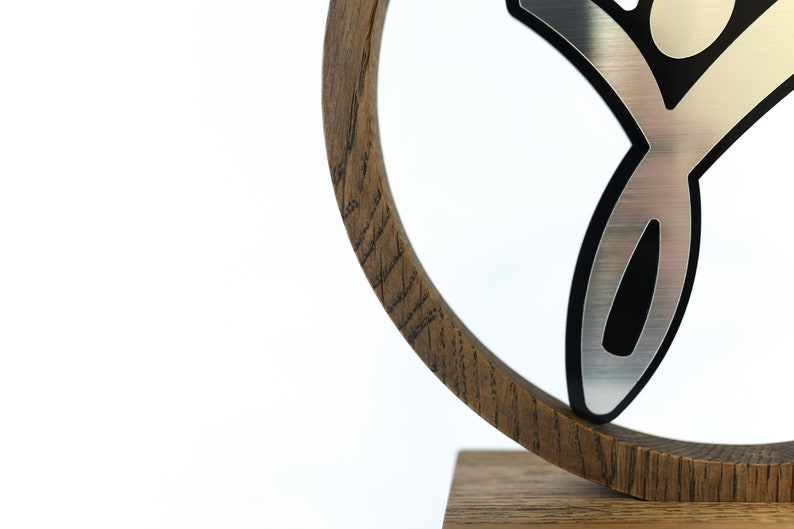 May include: A wooden award with a silver and black figure on top. The figure is a stylised person with arms raised in the air.