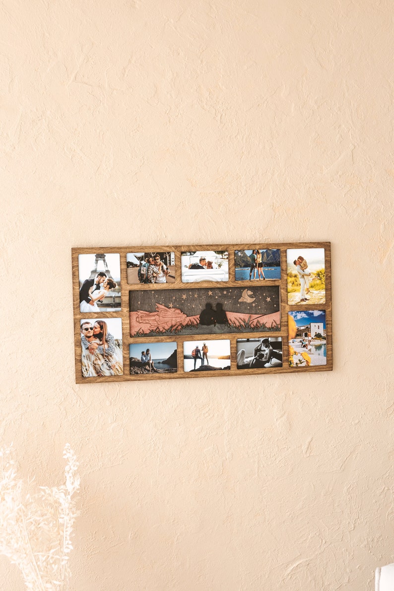 May include: A rectangular wooden collage photo frame featuring ten individual slots for photographs surrounding a central horizontal panel with a laser-cut silhouette of two people sitting under a starry sky and a crescent moon.