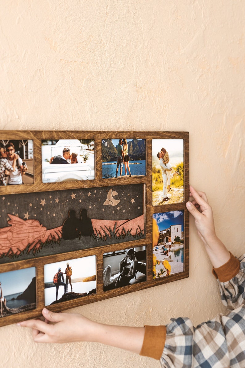 May include: A rectangular wooden collage photo frame with a dark brown finish, featuring multiple slots for photographs and a central decorative panel depicting a silhouette of two people sitting under a night sky with stars and a crescent moon.