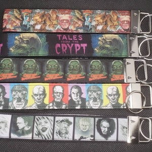 May include: Five keychains with various horror movie character designs. The keychains feature images of classic monsters and the text "TALES FROM THE CRYPT". Each keychain has a silver metal clasp and key ring.