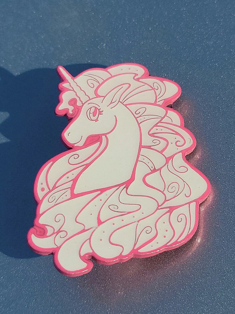 Puede incluir: Un unicornio blanco con un contorno rosa y una melena fluida. El unicornio est&aacute; representado en un estilo caprichoso con patrones en espiral en su melena.