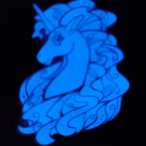 Puede incluir: Un pin de unicornio azul que brilla en la oscuridad con un dise&ntilde;o detallado. El unicornio tiene una melena y una cola fluidas, y un cuerno.