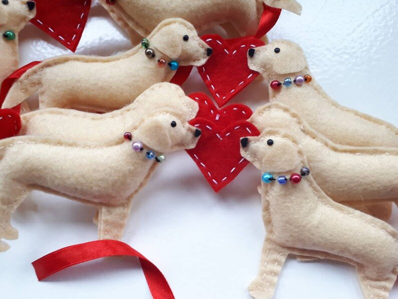 May include: Five felt dog ornaments with red hearts and beaded collars. The dogs are cream colored and have black eyes. The ornaments are perfect for a Valentine's Day theme.