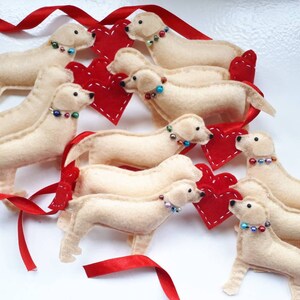 May include: A garland of felt golden retriever dog ornaments with red felt hearts. Each dog has a beaded collar with colorful beads.