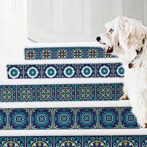 May include: Staircase with decorative tile stickers. The stickers feature a repeating pattern of blue, teal, and yellow floral designs on a dark blue background. The stairs are white with a white dog standing on the steps. The text "100% removable by StickersColoray Etsy Shop" is visible.