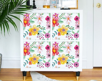 May include: A white cabinet with four drawers, each decorated with a floral pattern in shades of pink, yellow, and green. The cabinet is sitting on a white cowhide rug.